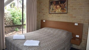Una habitación de hotel con cama, un cuadro en la pared y una ventana con cortinas.
