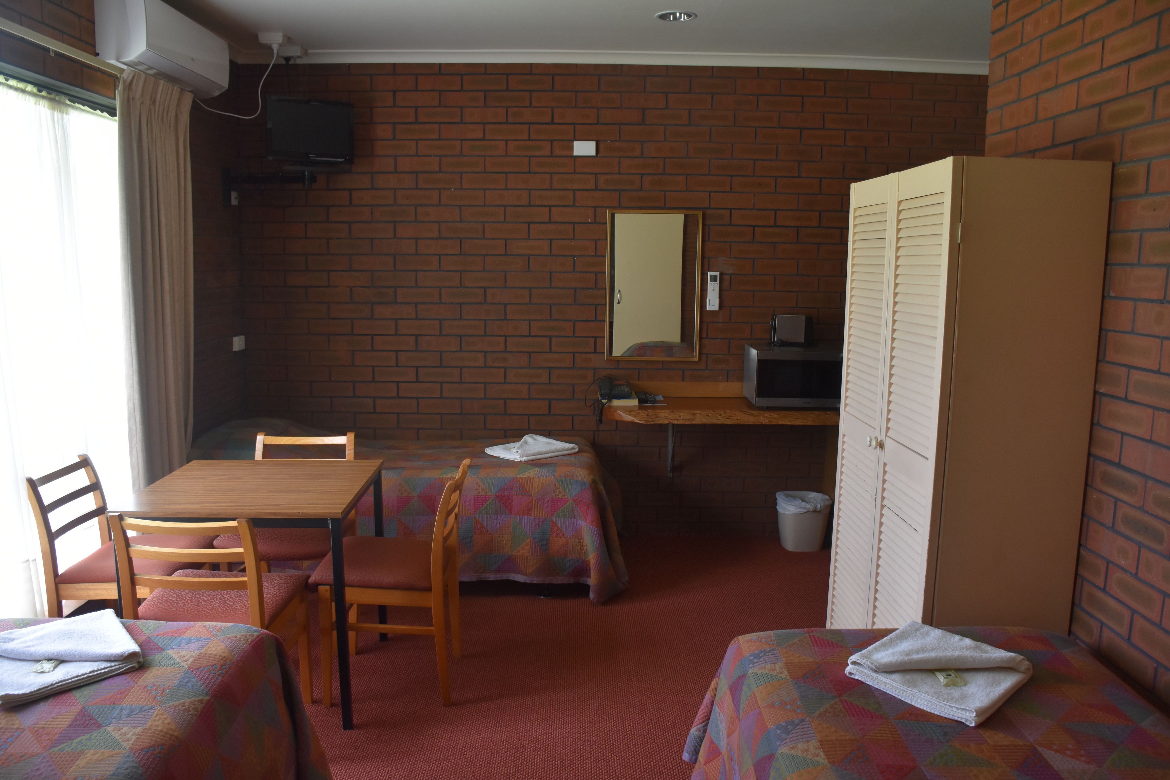 A room with two beds, a desk, a chair, a television, and a wardrobe.