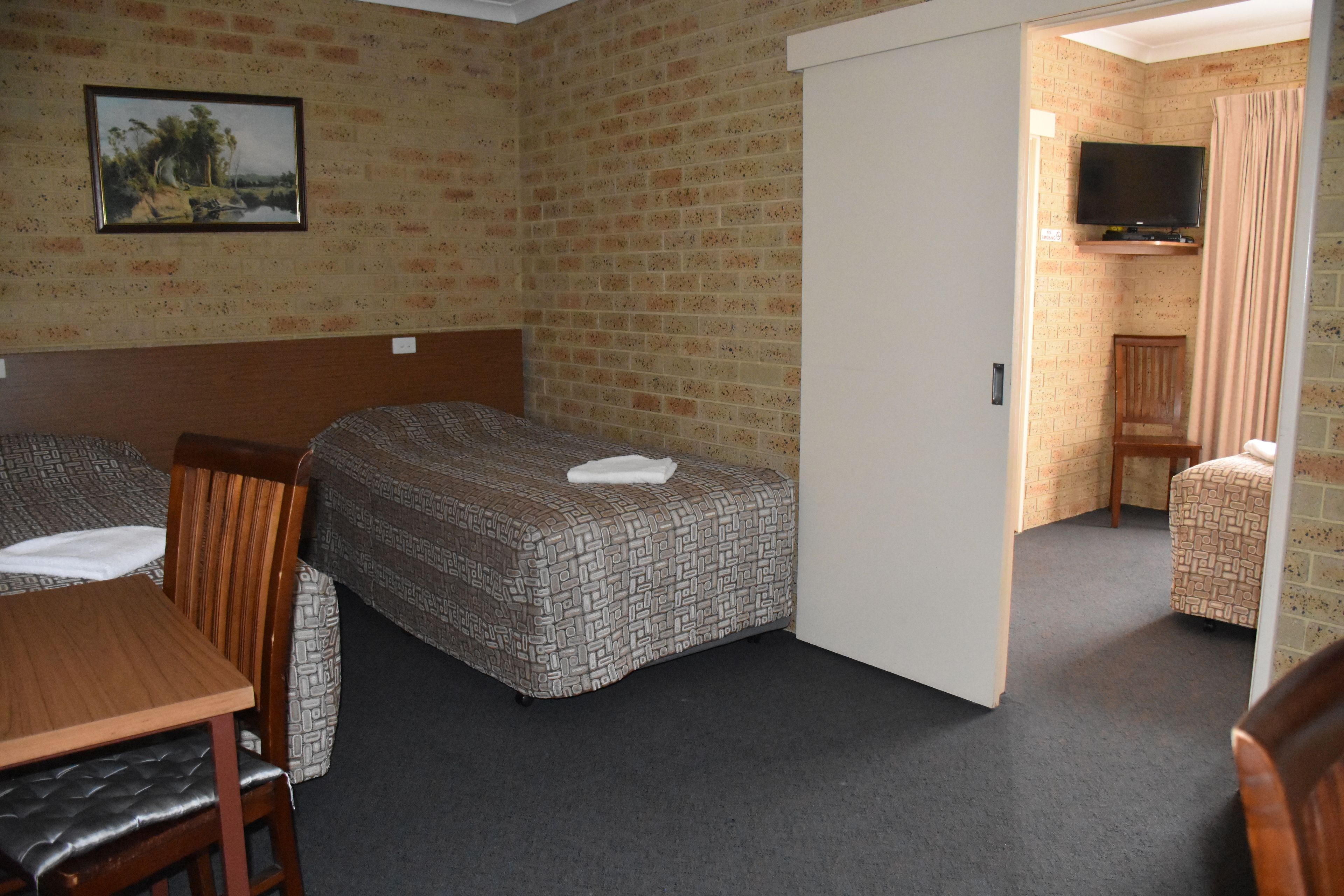 A room with two beds, a TV, and a painting on the wall.