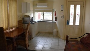 Una cocina compacta con comedor, un ventanal pequeño y una puerta con detalles de vidrio.