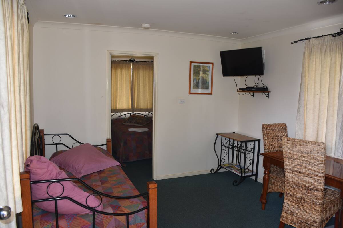 A bedroom with a bed, a chair, a television, and a small table.