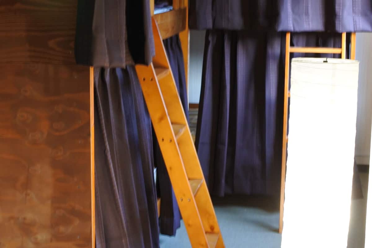 A room with a bunk bed, a wooden ladder, and a standing lamp.