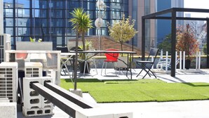 An outdoor seating area with a table and chairs, surrounded by concrete blocks and a small patch of grass. - Kagoshima Guest House M104 - Hostel (Kagoshima)