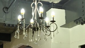 A dining area with a chandelier, chairs, and a table with a plant. - Kagoshima Guest House M104 - Hostel (Kagoshima)