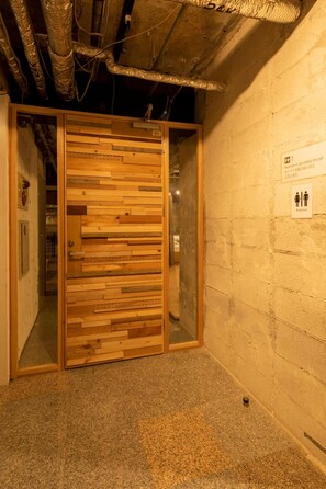 A wooden door with a glass panel, a sign indicating a restroom, and a brick wall. - Kagoshima Guest House M104 - Hostel (Kagoshima)