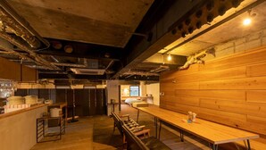 A spacious kitchen area with wooden countertops, a long wooden table, and a bench. - Kagoshima Guest House M104 - Hostel (Kagoshima)