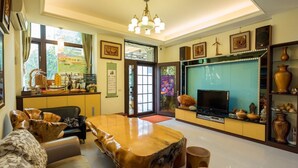 A spacious living room with a wooden dining table, comfortable seating, a flat-screen TV, and decorative items. - Sweet Dream Homestay (Magong)