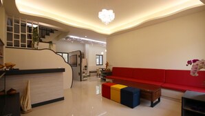 A modern living room with a red sofa, a coffee table, and a staircase leading to an upper level. - Sweet Dream Homestay (Magong)