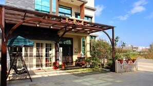 A modern two-story house with a covered patio area, large windows, and a garden. - Sweet Dream Homestay (Magong)