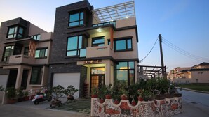 A modern two-story house with a garage, a balcony, and a well-maintained garden with potted plants. - Sweet Dream Homestay (Magong)