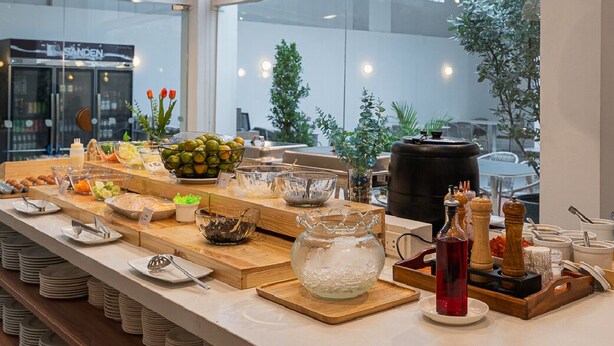 A buffet setup with various food items and a large window view. - Glai Gan Place Hotel (Saraburi)