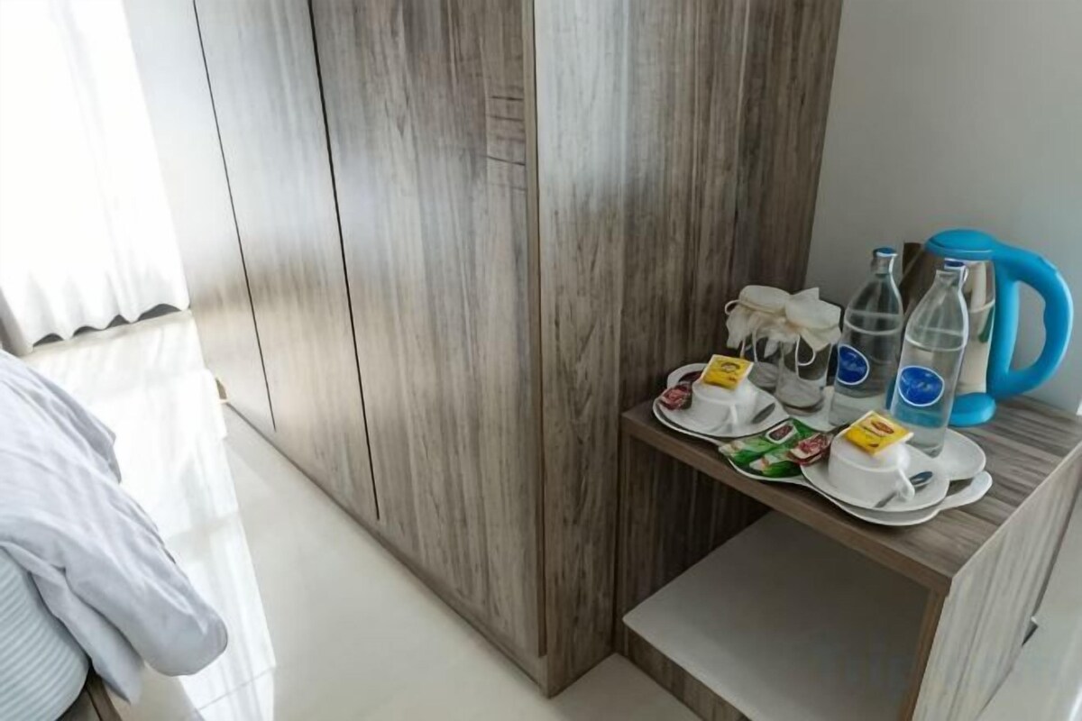 A hotel room with a wooden wardrobe, a small table with breakfast items, and a blue kettle.
