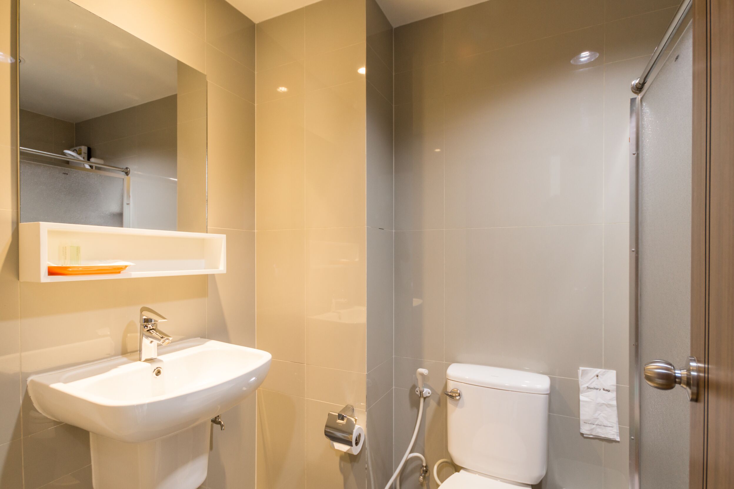 A modern bathroom with a sink, mirror, and toilet.