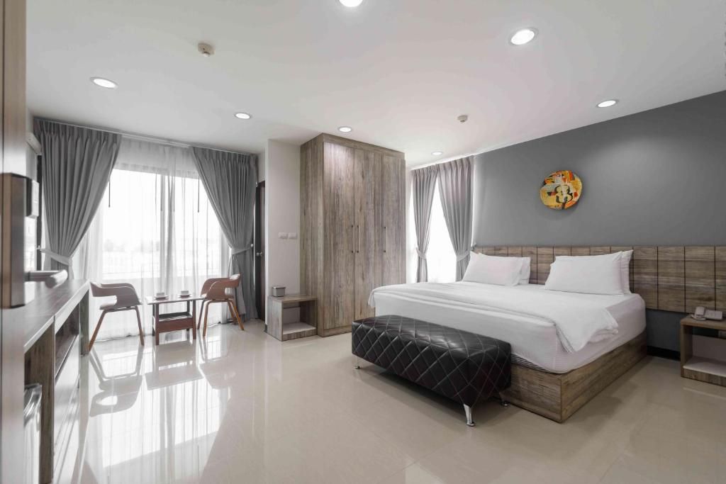 A modern hotel room with a large bed, a desk, and a chair.