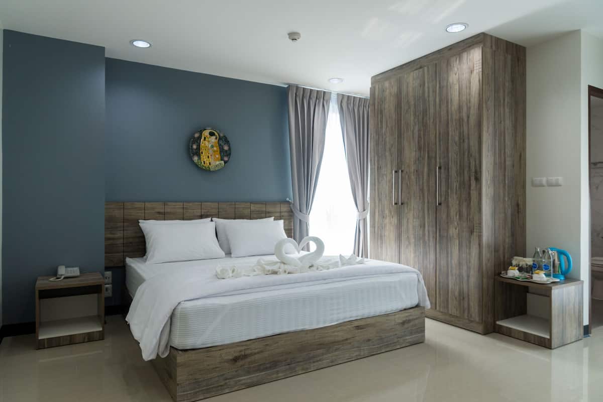 Un dormitorio moderno con una cama grande, cabecera de madera, una mesita de noche, un armario y un adorno en la pared.
