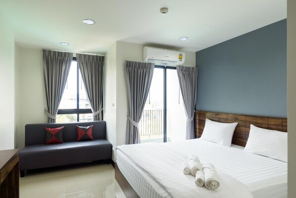 A hotel room with a bed, a sofa, and a window with curtains. - Glai Gan Place Hotel (Saraburi)