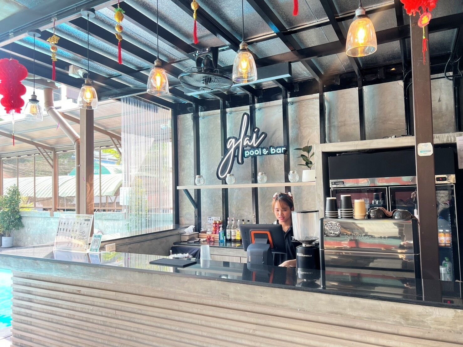 A pool bar with a glass counter, a sign reading "Gai Pool & Bar", and a coffee machine.