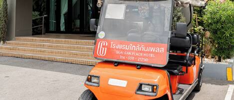 An orange golf cart parked in front of the Glai Gan Place Hotel.