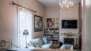 A cozy living room with a sofa, a fireplace, a television, and a chandelier. - Azalea Cedar-Rose Villa (Lyndoch)