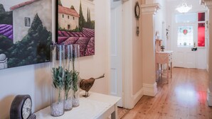 A hallway with a white door, a clock, and three vases with plants. - Azalea Cedar-Rose Villa (Lyndoch)
