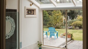 A bathroom with a large bathtub, a glass shower enclosure, and a view of a patio with outdoor furniture. - Azalea Cedar-Rose Villa (Lyndoch)