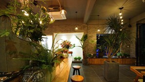 Un interior modern amb un taulell de recepció de fusta, plantes en testos i làmpades penjants.