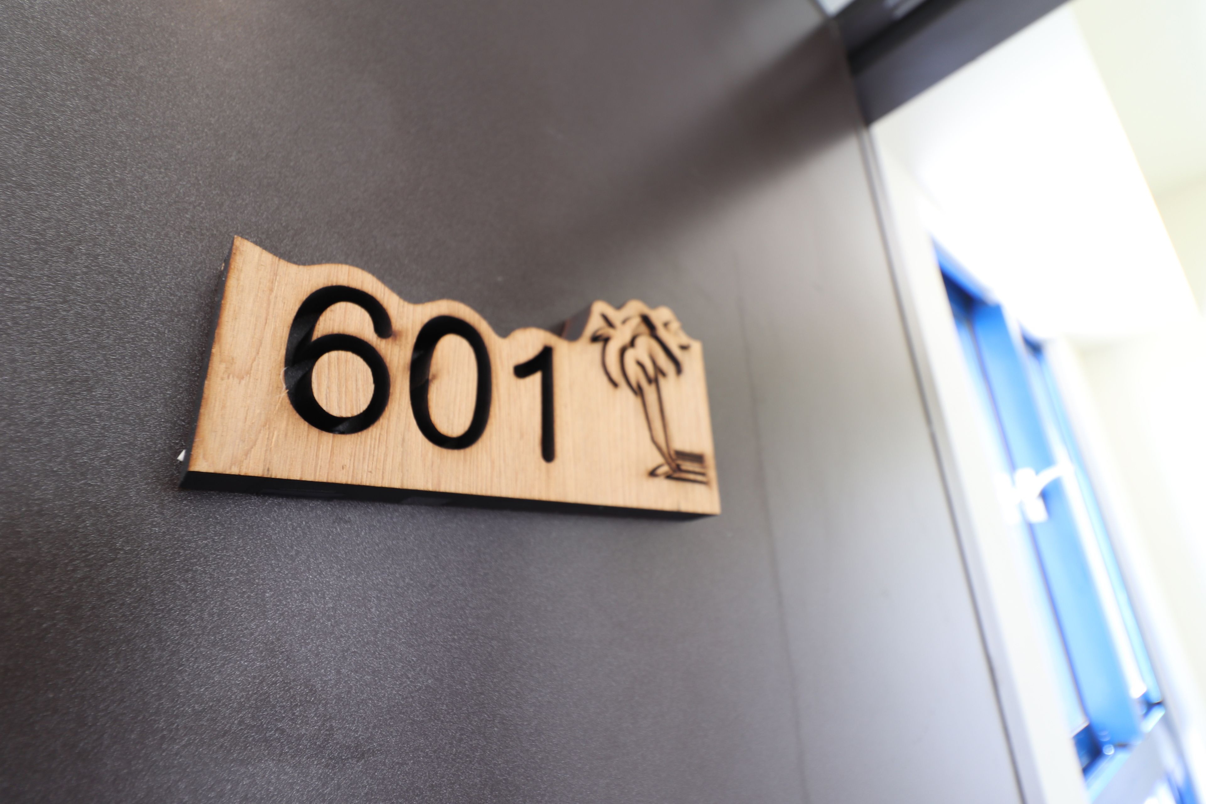 A wooden sign with the number 601 on a dark wall.