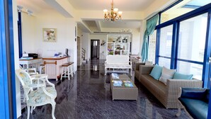Un vaste salon agrémenté d’un lustre, d’un ensemble de canapés, d’un coin repas et d’un escalier menant à un autre niveau.