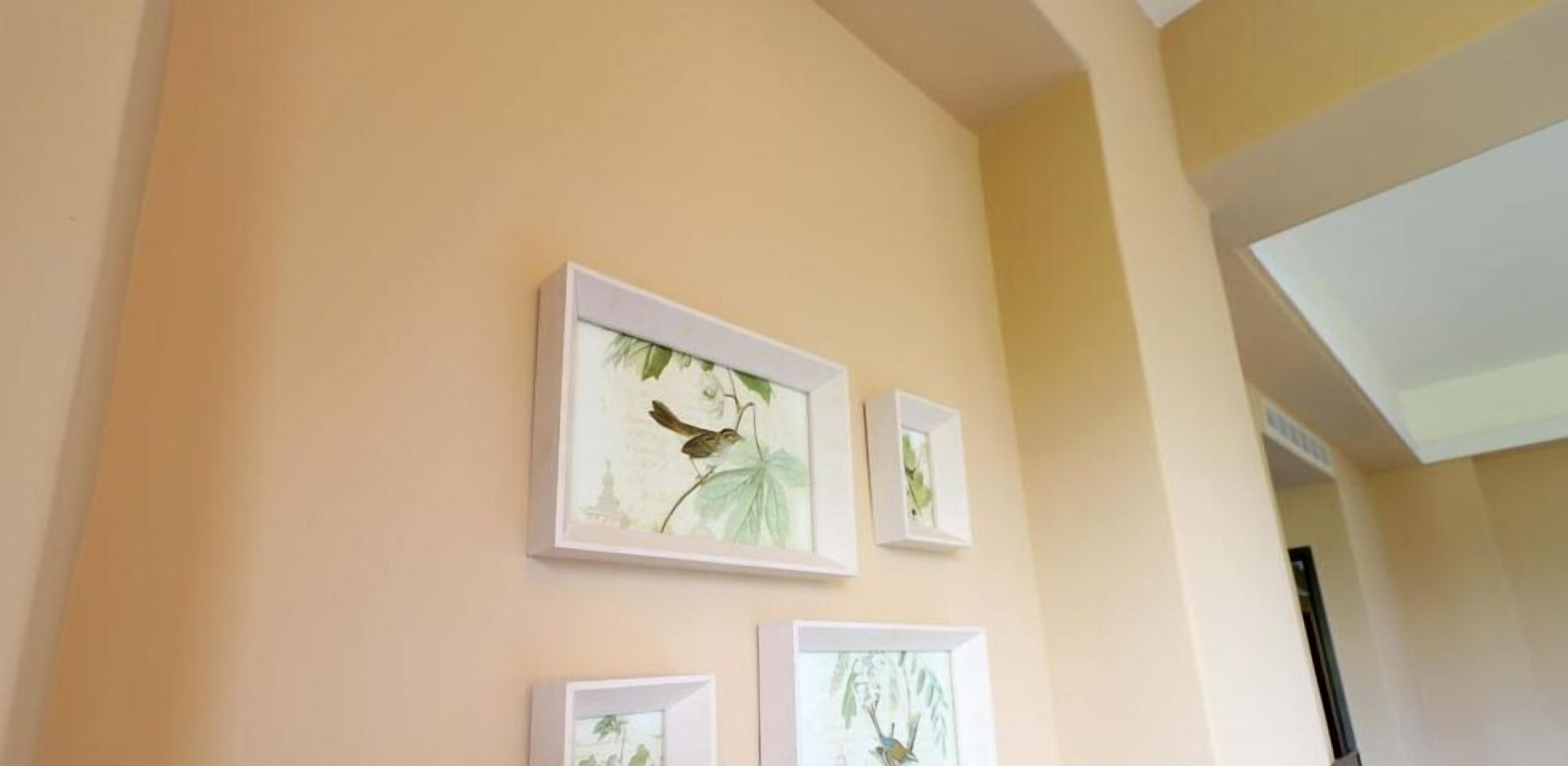 A hallway with framed artwork on the wall, a ceiling with a skylight, and a door at the end.