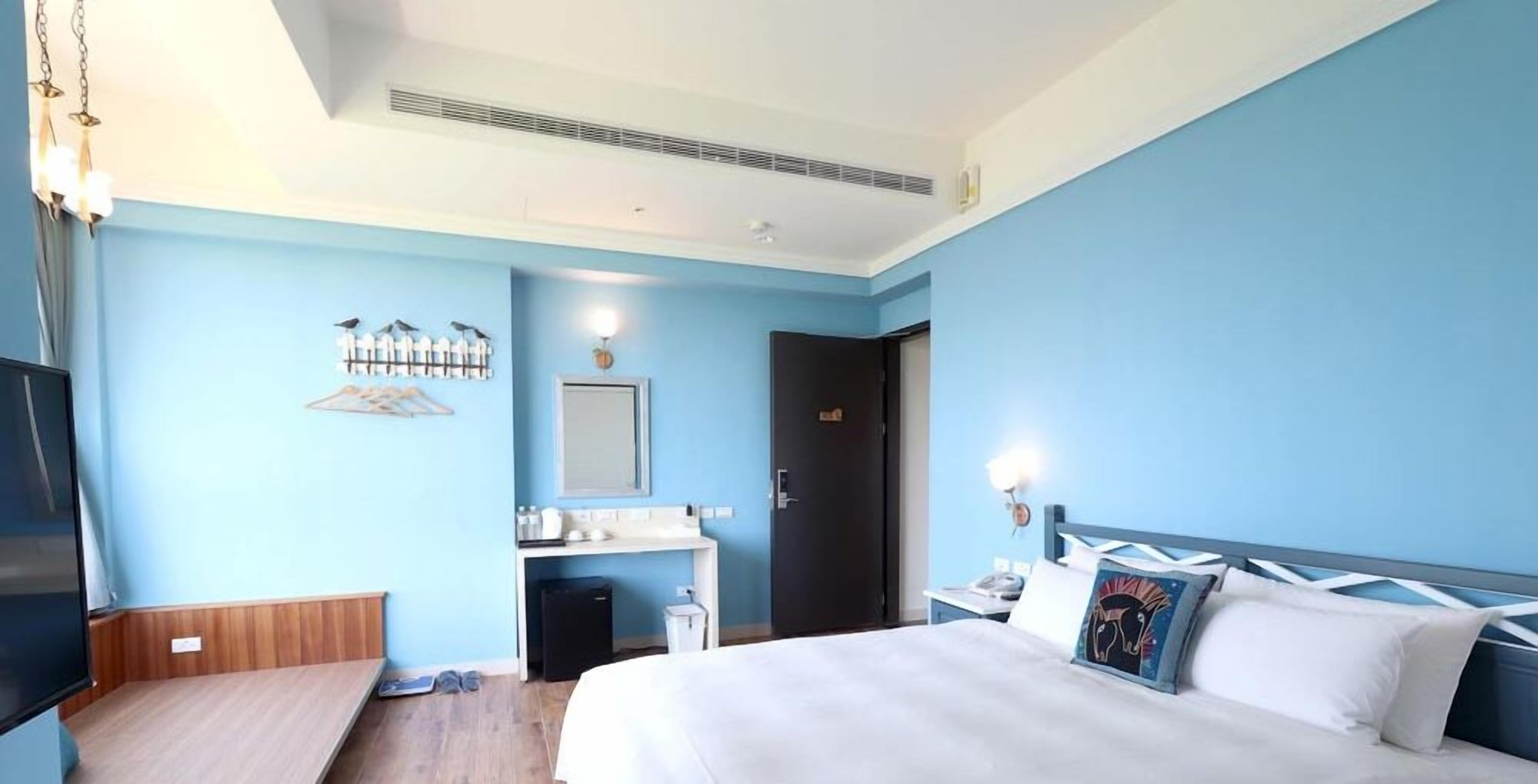 Una habitación de hotel con cama, escritorio, televisor y baño.