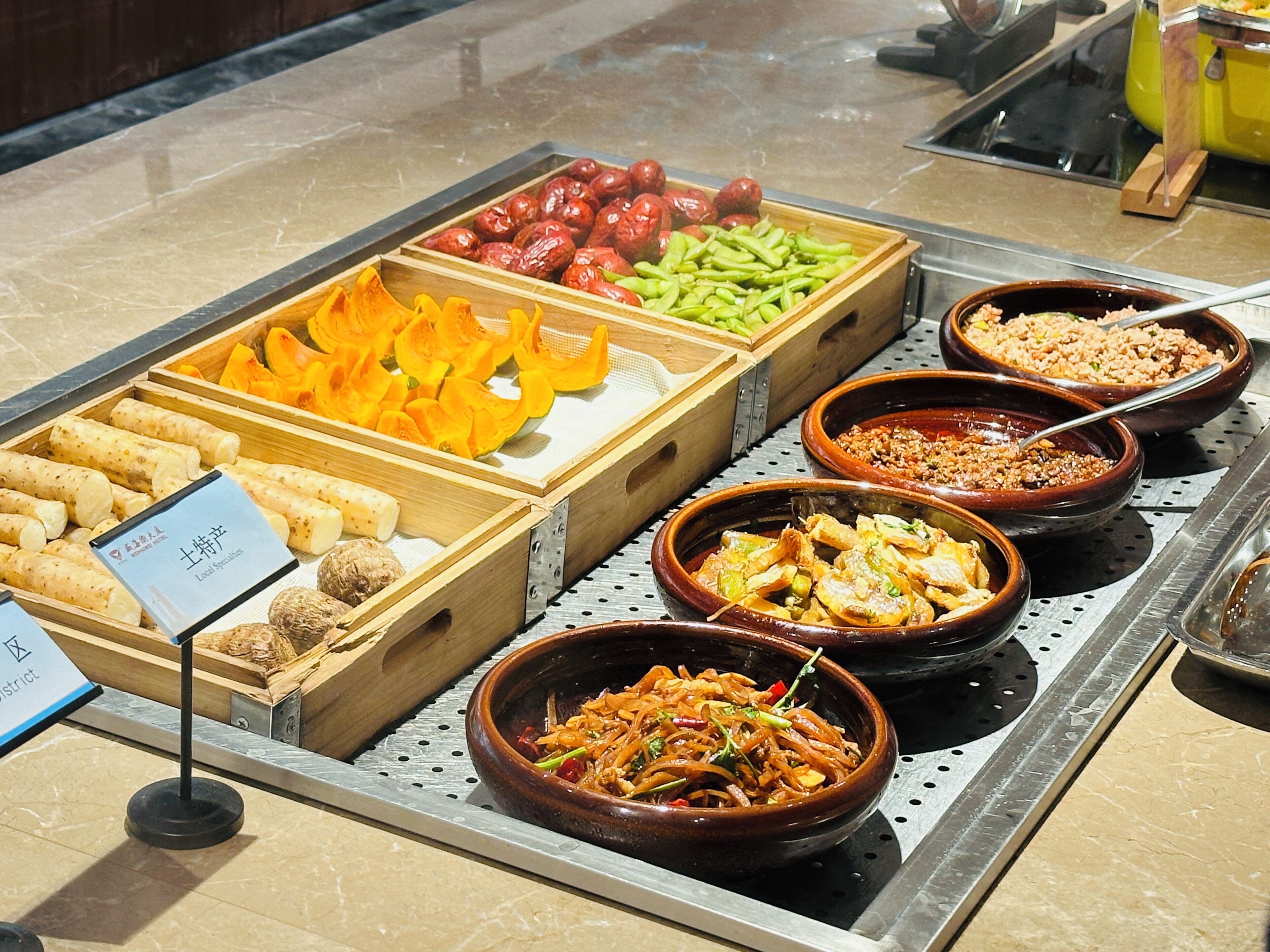 A buffet with various food items including fruits, vegetables, and dishes in ceramic bowls.
