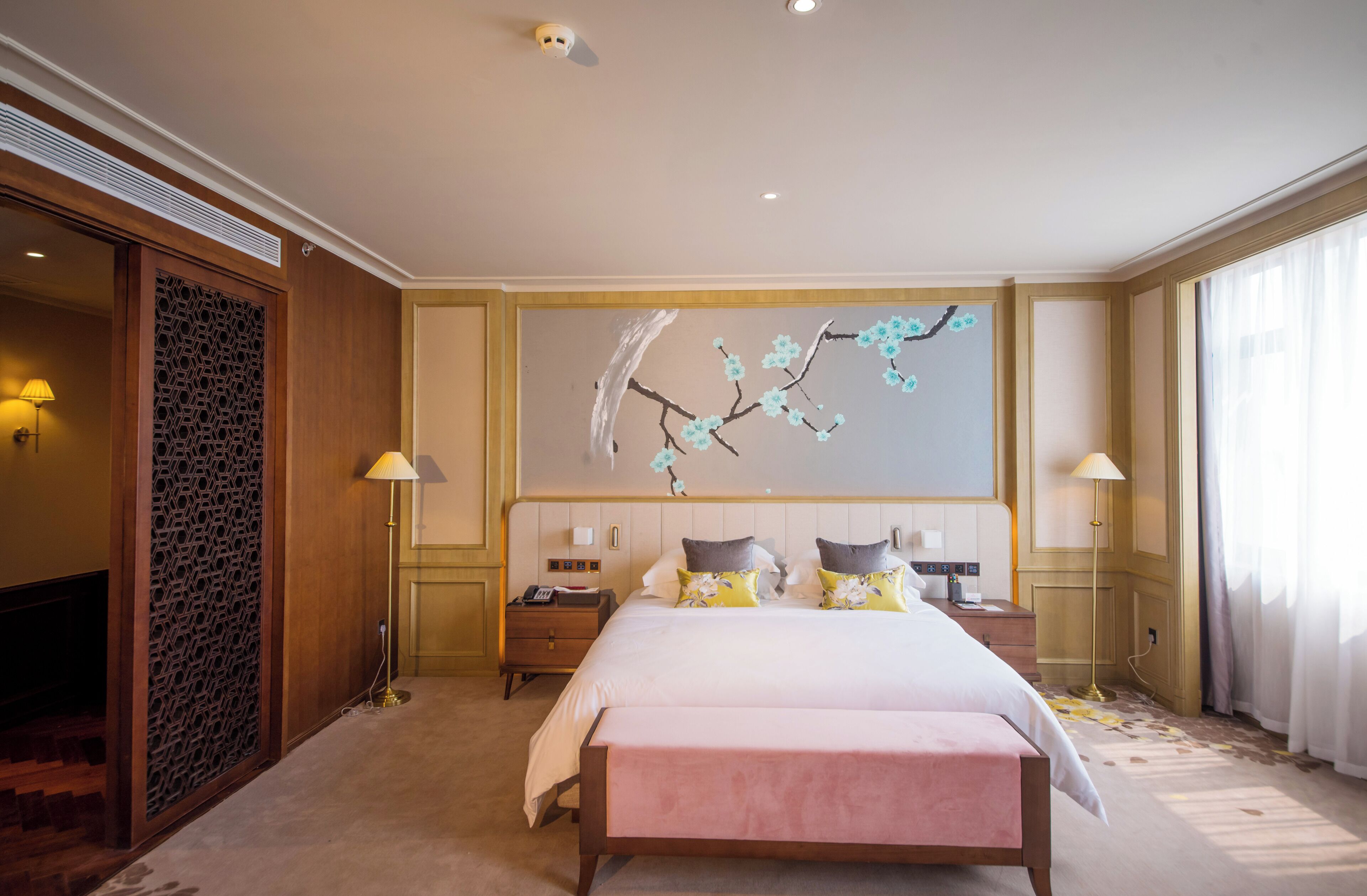 Habitación de hotel con una cama grande, dos mesitas de noche, un adorno en la pared y un panel de madera.