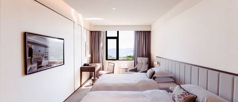 Habitación de hotel con dos camas, un escritorio, una silla, un televisor y una ventana con vistas.