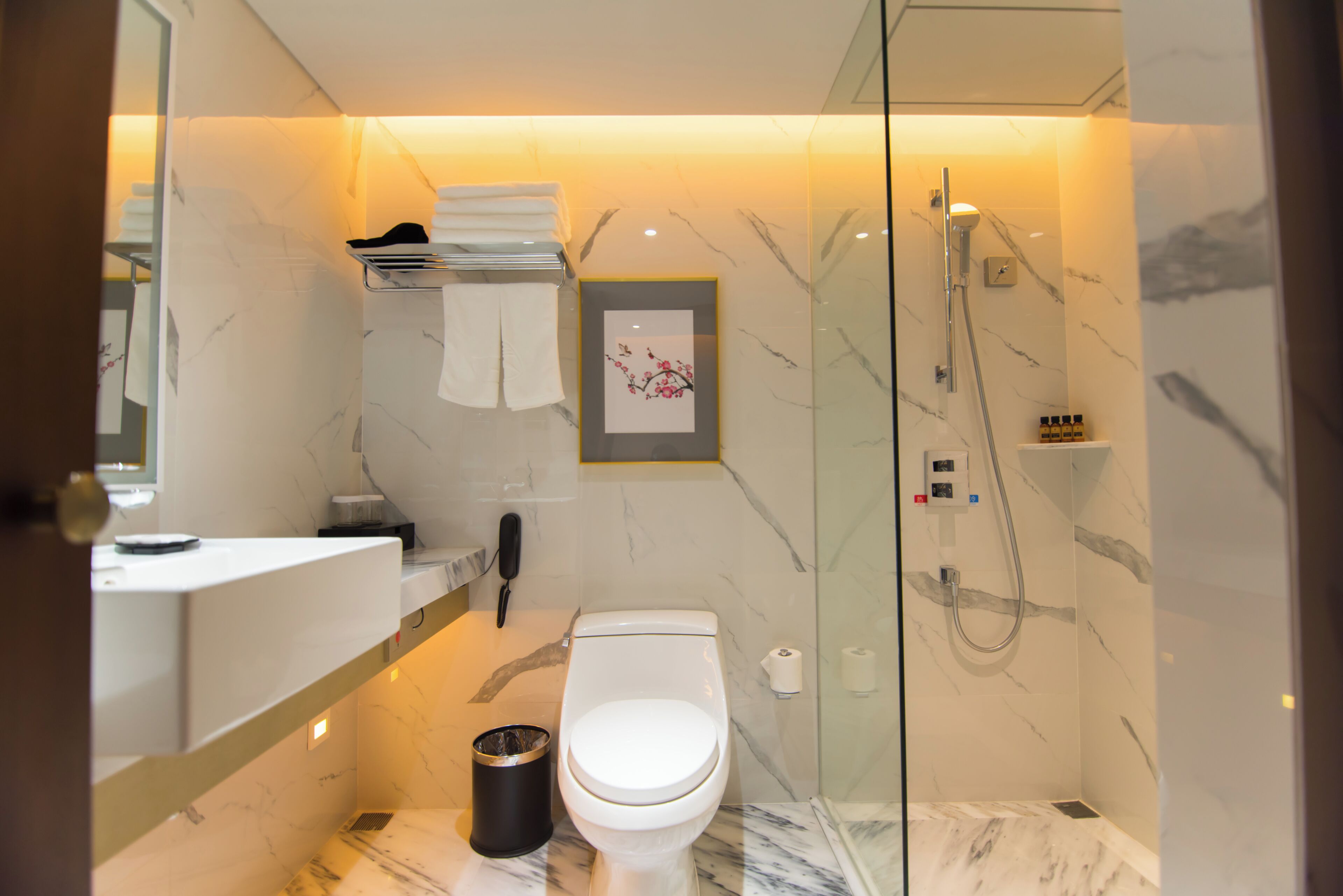 A modern bathroom with a marble sink, toilet, and shower.