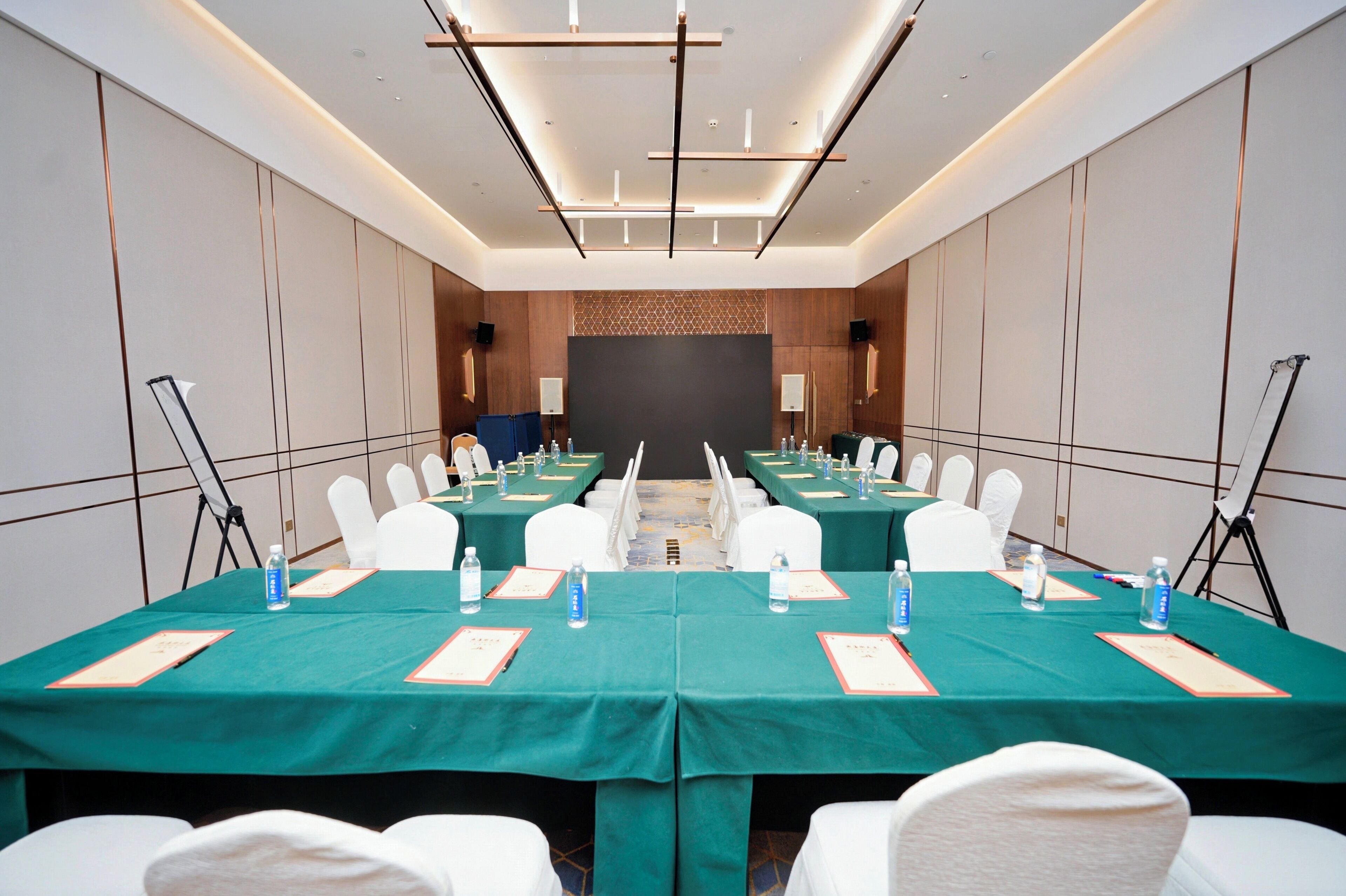A conference room with a long table, white chairs, and water bottles.