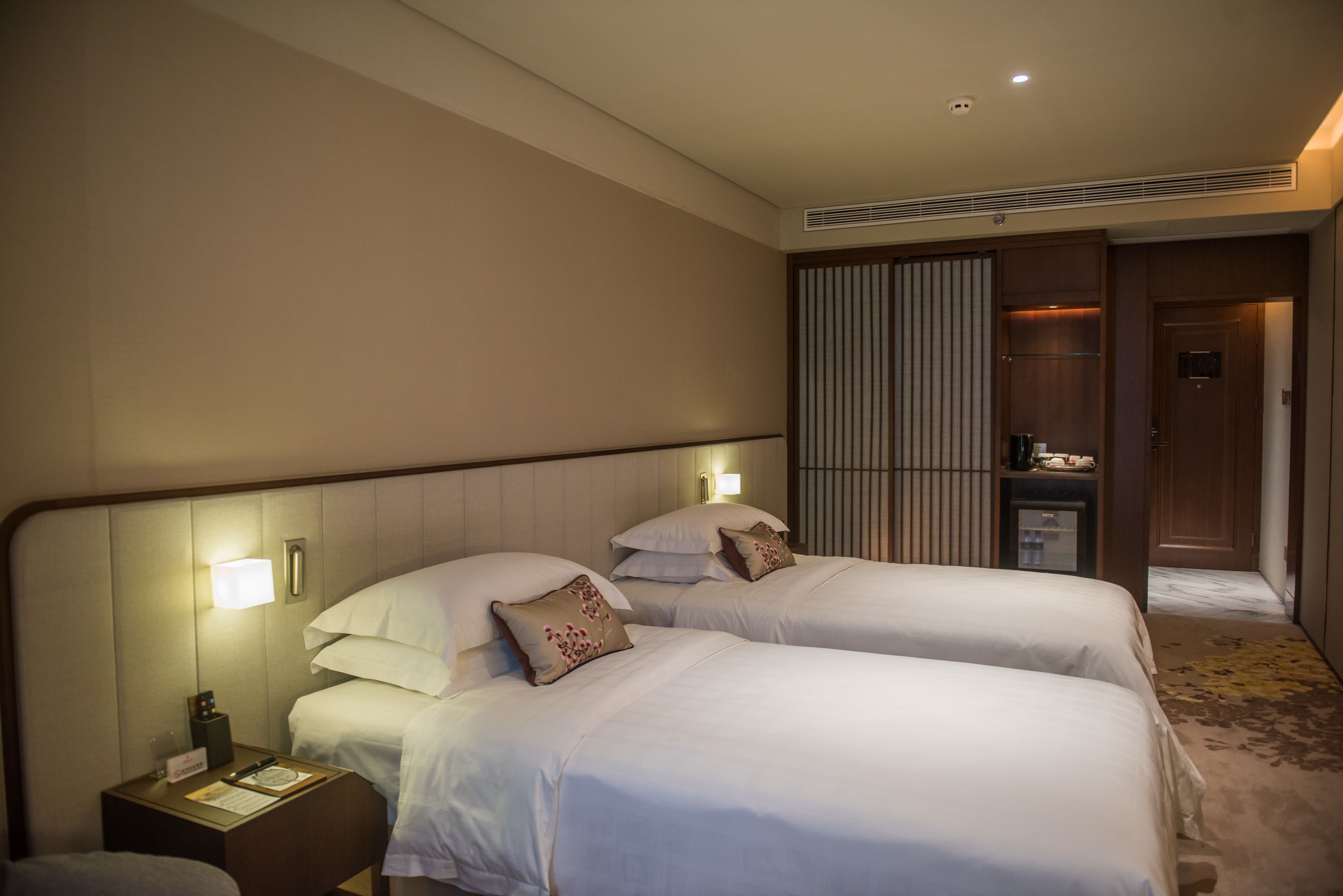 Una camera d'albergo con due letti, un comodino, una scrivania e un armadio.