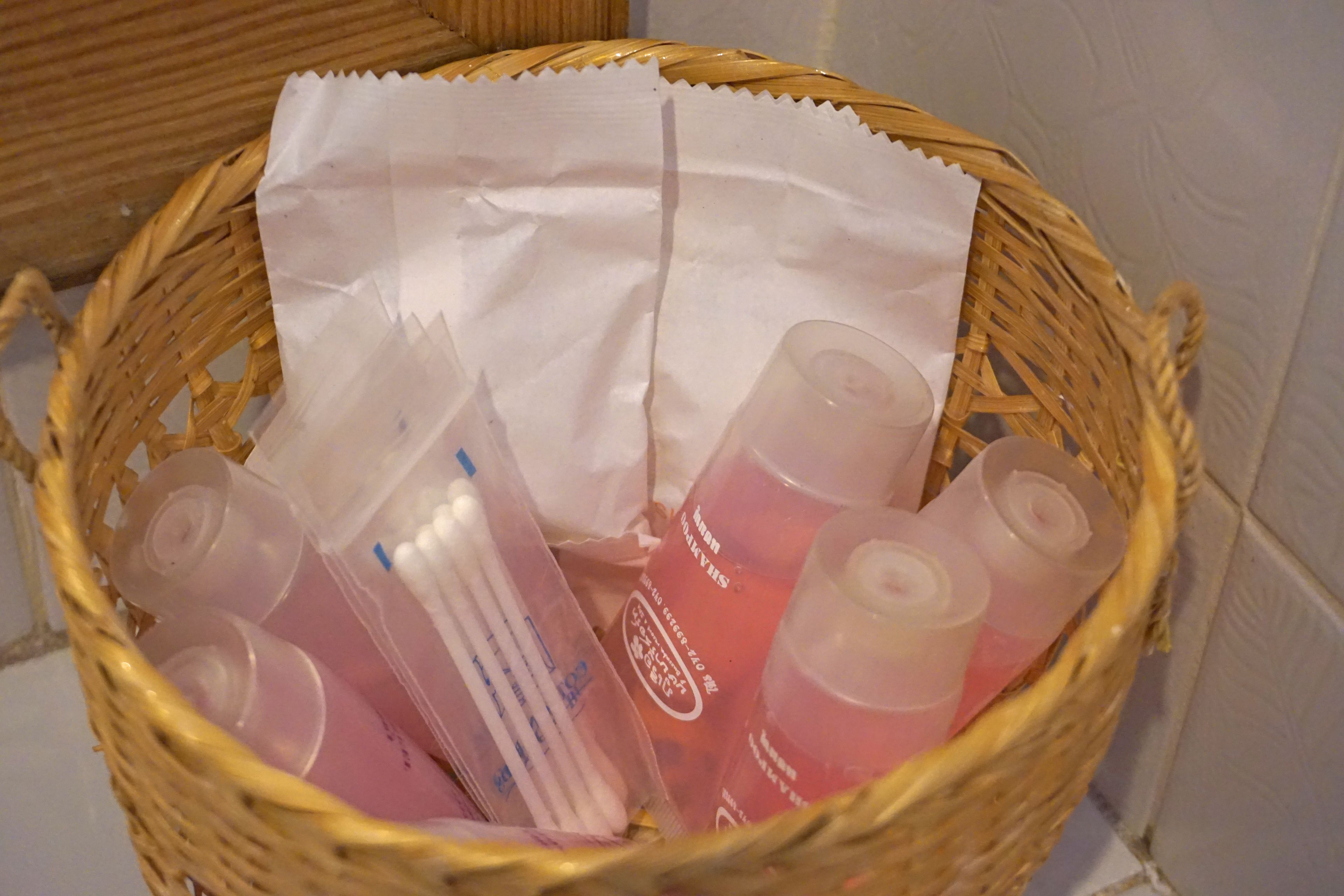 A wicker basket containing several plastic bottles and a tissue.