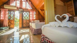 Una cabaña de madera acogedora con dos camas, un balcón y una decoración con forma de corazón en una toalla.