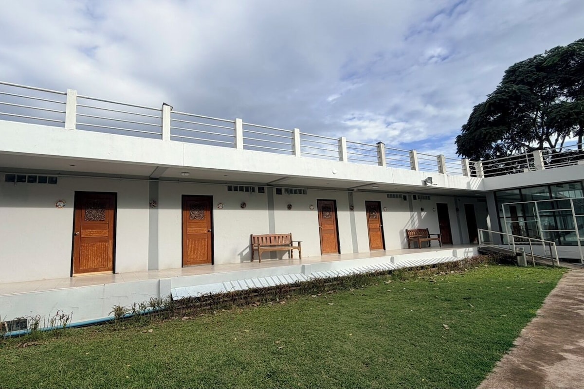Un edificio moderno con techo plano, paredes exteriores blancas y una serie de puertas de madera.