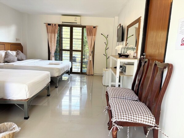 Habitación de hotel con dos camas, un escritorio, una silla, un televisor y una ventana con cortinas.