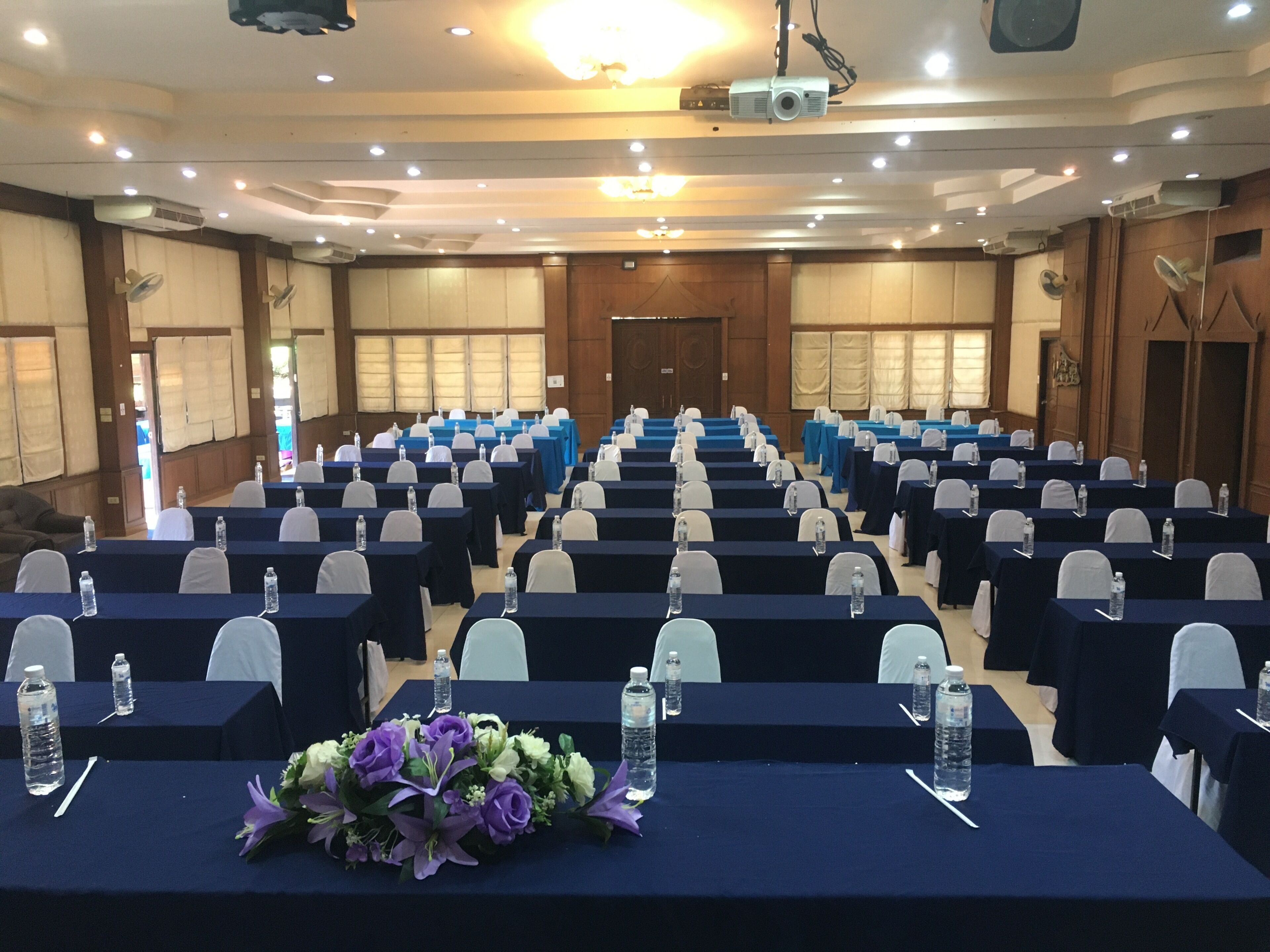 A conference room with rows of tables, chairs, and a projector screen.