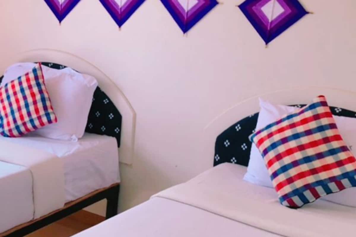 Quarto de hotel com duas camas, cada uma com almofada e toalha.