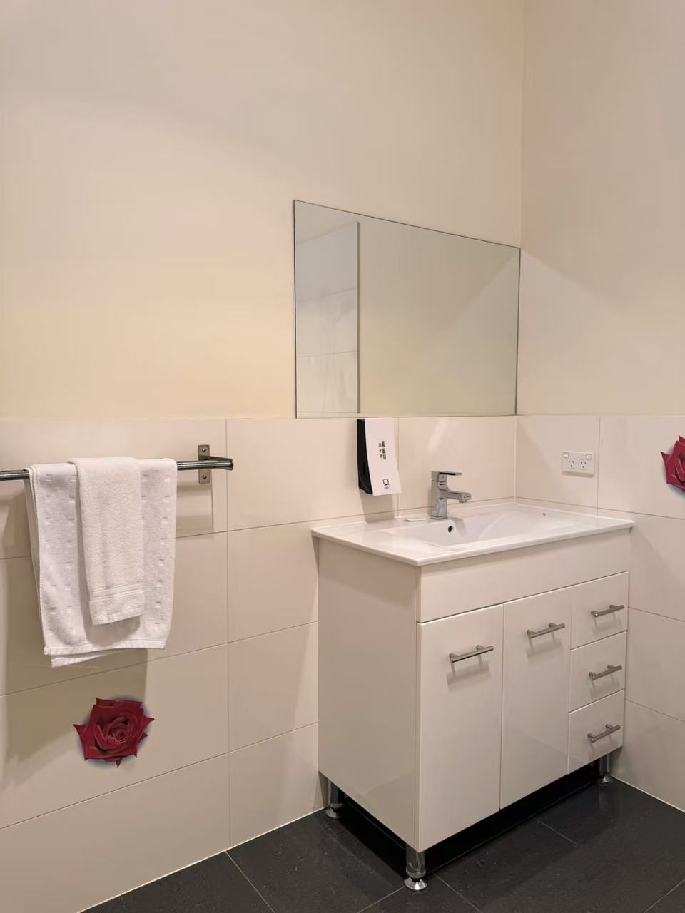 A modern bathroom with a white sink, mirror, and cabinets.