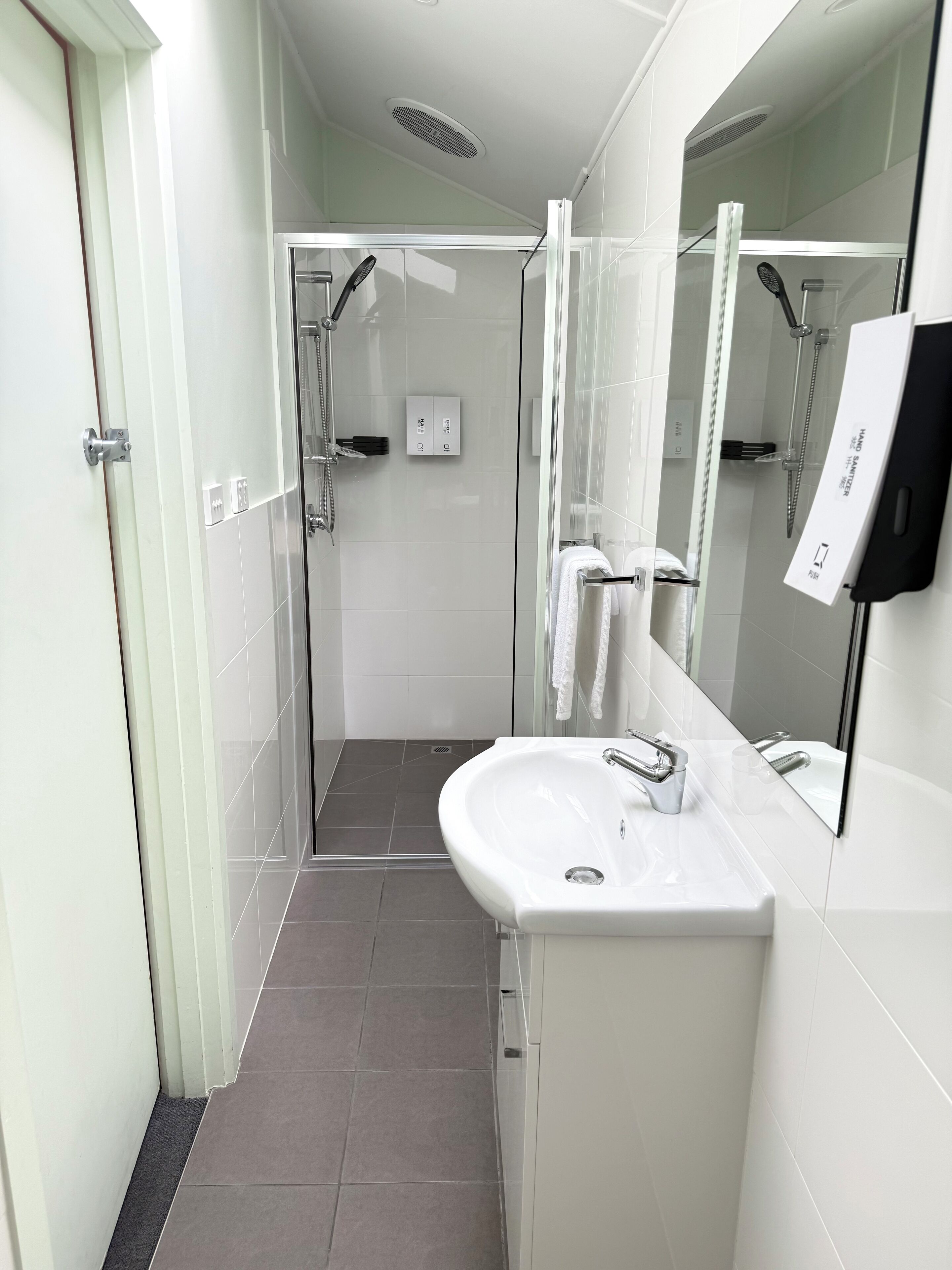 A modern bathroom with a glass-enclosed shower, a white sink, and a large mirror.