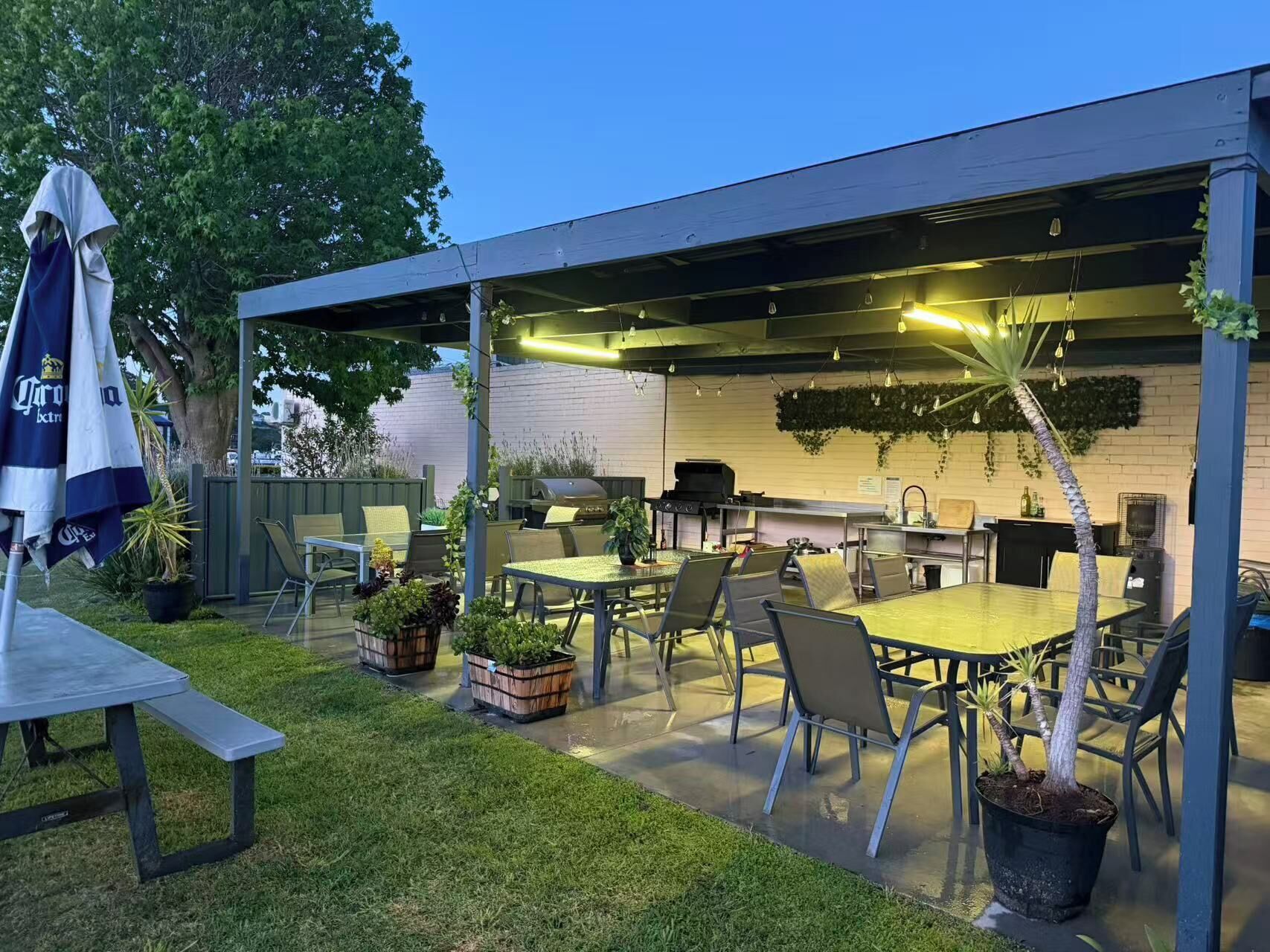 An outdoor patio area with a covered seating area, a grill, and potted plants.