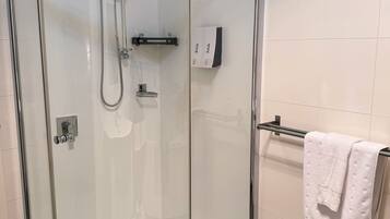 Une douche fermée par des parois en verre, dotée d’un pommeau de douche à main et d’un panneau de commande fixé au mur.