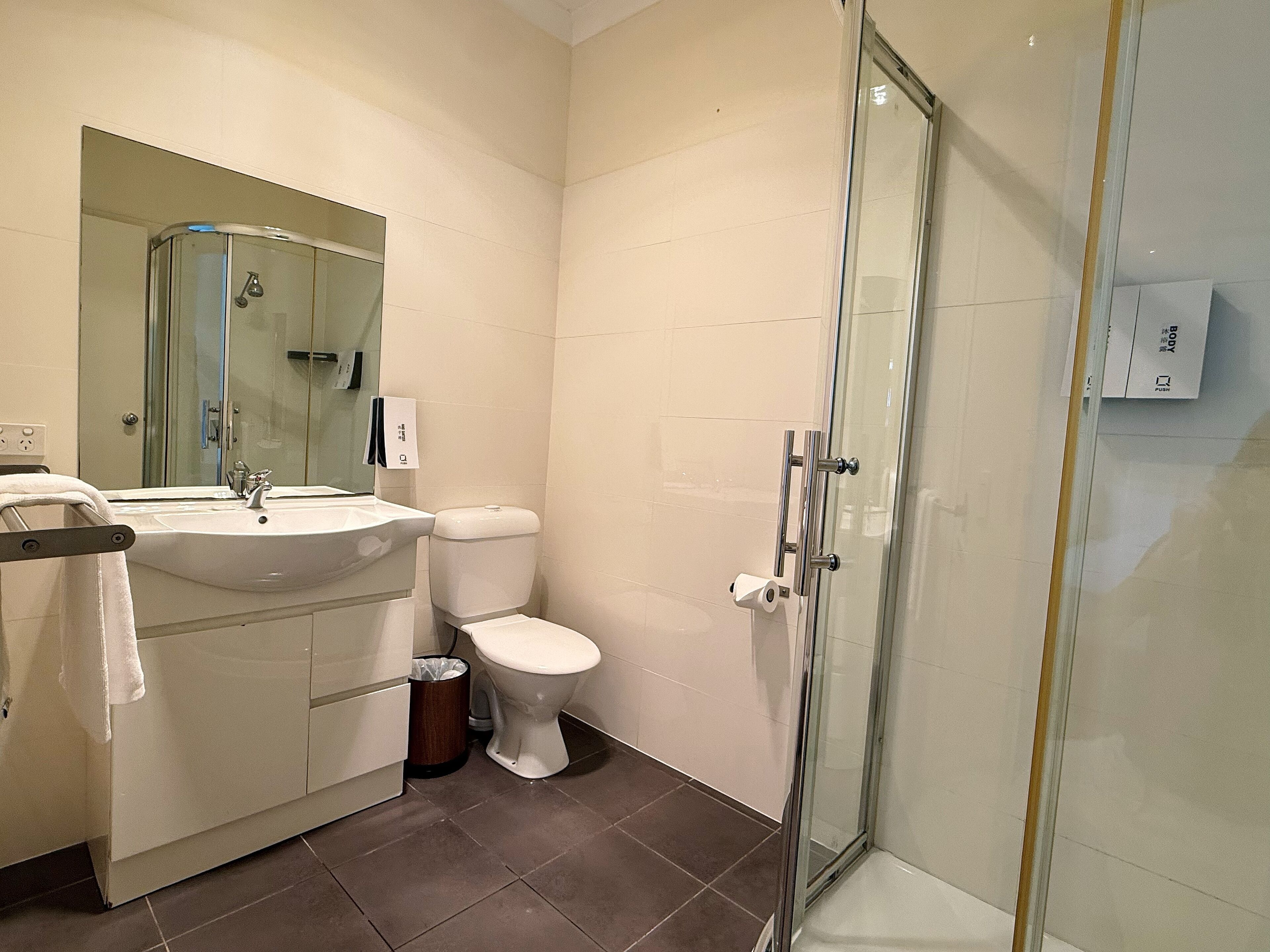 Ein modernes Badezimmer mit Duschkabine aus Glas, einem weißen Waschbecken und einer Toilette.