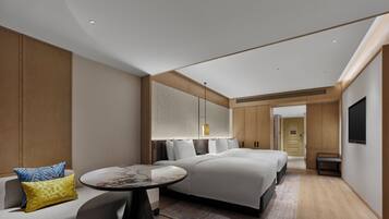 A modern hotel room with a bed, a sofa, a round table, and a TV.