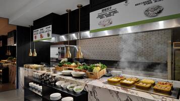A modern kitchen with marble countertops, stainless steel appliances, and a variety of food items displayed.