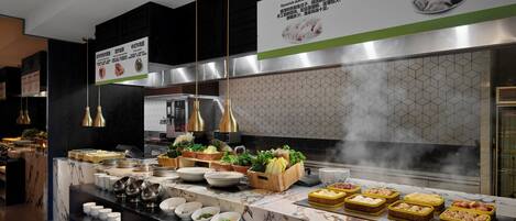 A modern kitchen with marble countertops, stainless steel appliances, and a variety of food items displayed.
